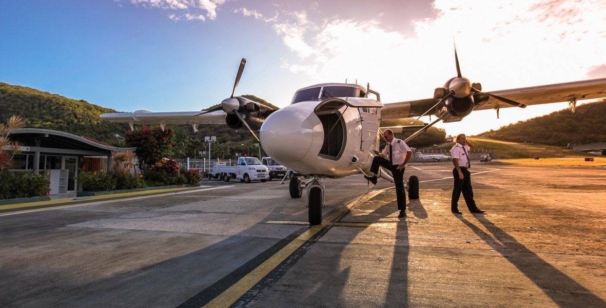 Small turboprop aircraft on the runway at Gustaf III Airport in St Barts with the Caribbean visible at the runway edge