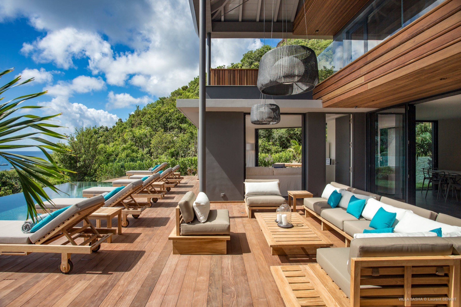 Open-air teak deck with outdoor lounge and hillside ocean view