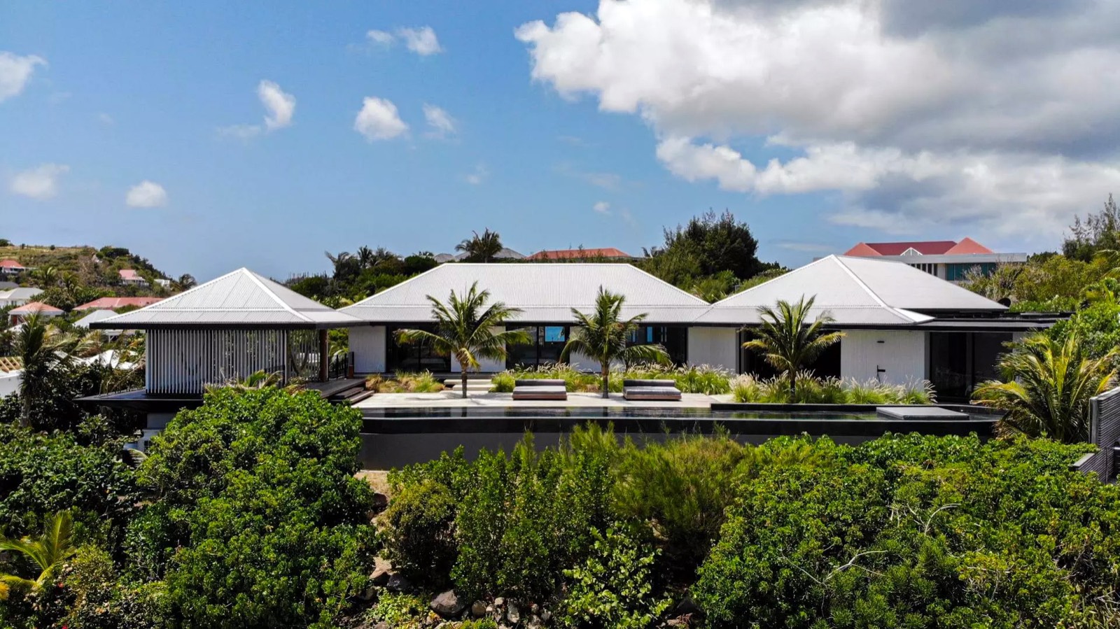 Aerial view of a hillside villa in St. Barth with red rooftops and tropical landscaping